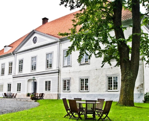 Mansión señorial blanca rodeada de jardines y árboles en paisaje rural de Suecia