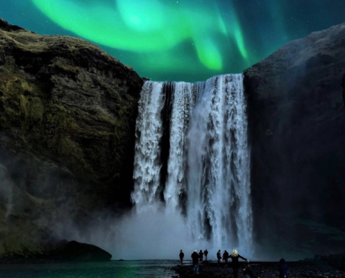Auroras boreales sobre la cascada Skógafoss en paisaje nocturno de Islandia