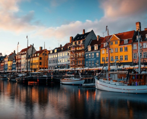 Nyhavn al atardecer con casas de colores y veleros amarrados en el canal de Copenhague
