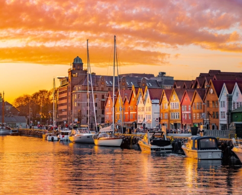 Casas de madera del muelle de Bryggen reflejadas en el agua al atardecer en Bergen, Noruega