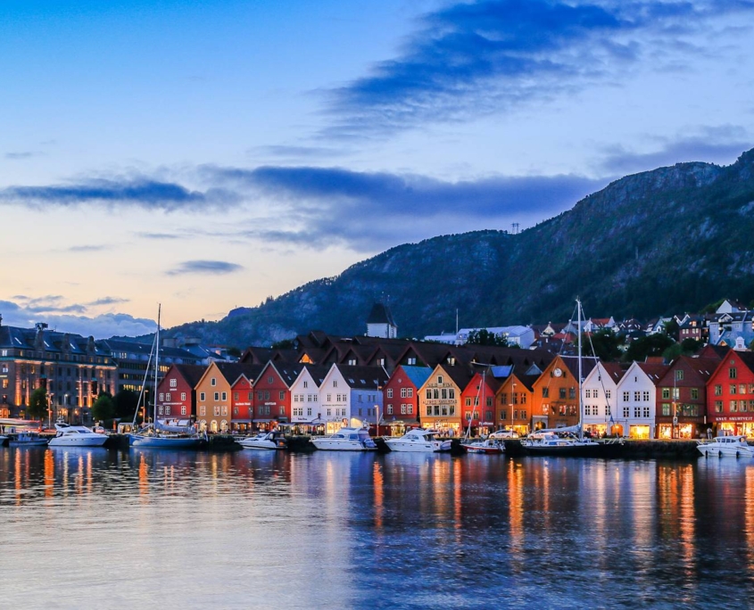 Vista panorámica de Bergen con Bryggen iluminado y montañas de fondo, imagen del viaje Capitales Escandinavas y Fiordos