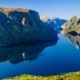 Fiordo rodeado de montañas reflejadas en el agua con una embarcación navegando en Noruega