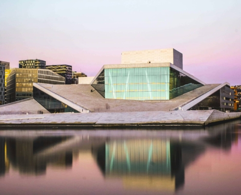 Ópera de Oslo al atardecer con fachada moderna reflejada en el agua del puerto
