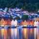 Fachadas de Bryggen en Bergen reflejadas en el agua al atardecer con luces encendidas