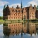 Castillo de Egeskov reflejado en el agua con fachada renacentista y jardines en Dinamarca