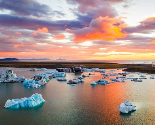 Icebergs flotando en laguna glaciar bajo cielo rosado al atardecer en Islandia