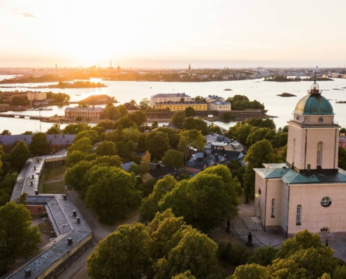 Vista aérea de Suomenlinna con islas verdes, fortificaciones y agua tranquila al atardecer en Helsinki