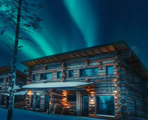 Cabaña de madera iluminada bajo auroras boreales entre bosques nevados en Ruka, Finlandia