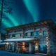 Cabaña de madera iluminada bajo auroras boreales entre bosques nevados en Ruka, Finlandia