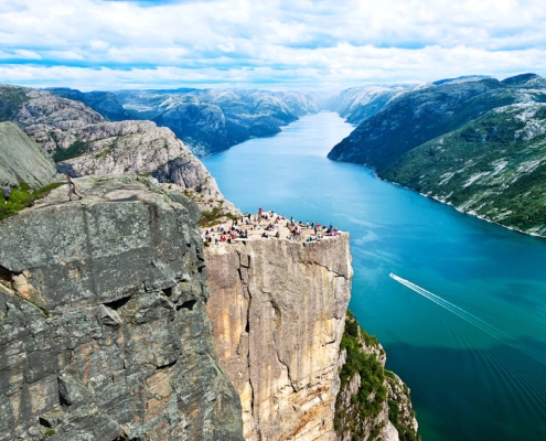 Vista del Preikestolen sobre el Lysefjord con senderistas en la cima y acantilados, Noruega