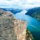 Vista del Preikestolen sobre el Lysefjord con senderistas en la cima y acantilados, Noruega