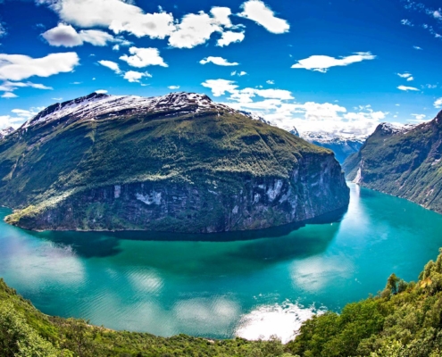 Vista aérea del fiordo de Geiranger con montañas, agua turquesa y cruceros, Noruega