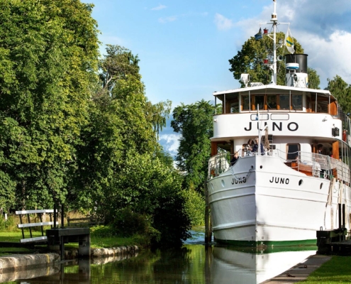 Barco clásico navegando por el canal de Göta entre vegetación y esclusas en Suecia