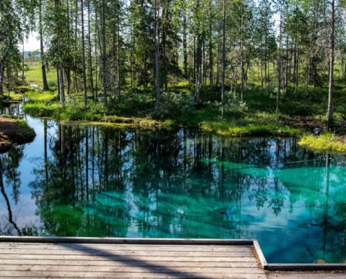 Piscina natural de agua clara rodeada de bosque y rocas en la región de los mil lagos de Finlandia