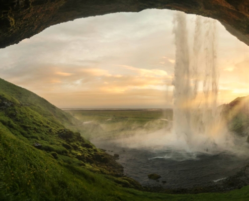 Cascada Seljalandsfoss vista desde praderas verdes con cielo cubierto en Islandia