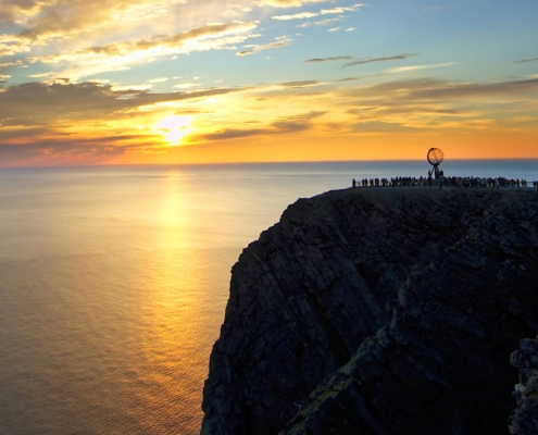 Costa rocosa iluminada por el sol de medianoche con mar en calma en Cabo Norte, Noruega