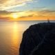 Costa rocosa iluminada por el sol de medianoche con mar en calma en Cabo Norte, Noruega