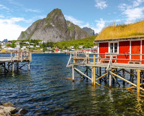 Cabaña de pescadores roja sobre pilotes frente al mar y montañas en Lofoten, Noruega