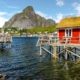 Cabaña de pescadores roja sobre pilotes frente al mar y montañas en Lofoten, Noruega