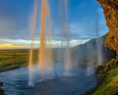 Cascada Seljalandsfoss frente a llanuras cubiertas de hierba y acantilado volcánico en Islandia
