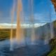Cascada Seljalandsfoss frente a llanuras cubiertas de hierba y acantilado volcánico en Islandia