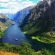 Fiordo estrecho rodeado de montañas con un barco navegando por aguas tranquilas en Noruega
