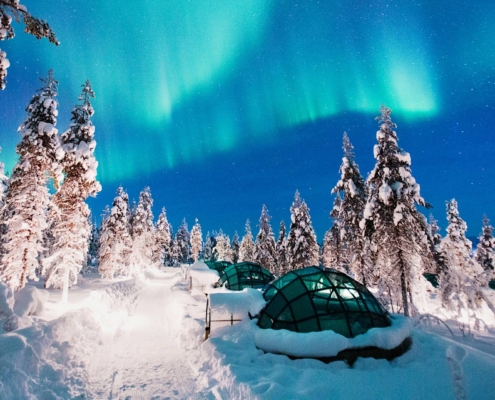 Paisaje nevado con iglús de cristal bajo auroras boreales en Kakslauttanen, Laponia finlandesa
