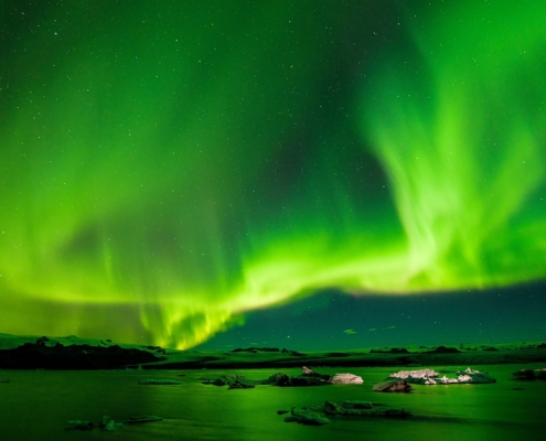 Auroras boreales iluminando el cielo nocturno sobre paisaje ártico en Tromsø, Noruega