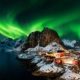 Cabañas de pescadores rojas junto al mar bajo auroras boreales en las islas Lofoten, Noruega