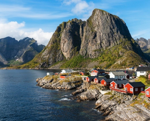 Casas rojas de pescadores en Reine junto al mar y montañas escarpadas en Lofoten, Noruega
