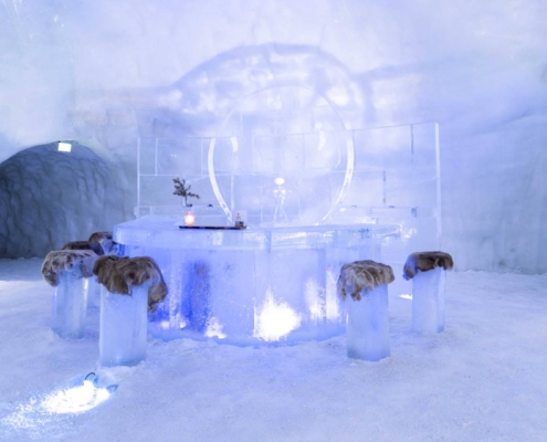 Hotel de hielo iluminado en tonos azules en entorno nevado de Kirkenes, Noruega