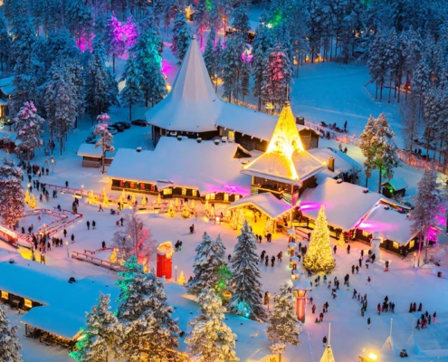 Aldea nevada de Papá Noel con edificios iluminados y luces festivas en Rovaniemi, Laponia