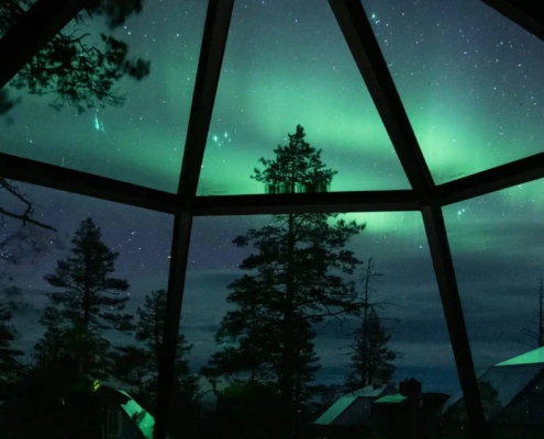 Auroras boreales sobre iglús de cristal en paisaje nevado de Laponia finlandesa