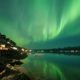 Cabañas iluminadas frente al fiordo de Malangen bajo auroras boreales en Tromsø, Noruega