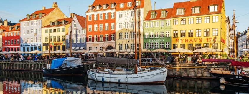 Canal de Nyhavn con casas de colores y barcos reflejados en el agua en Copenhague