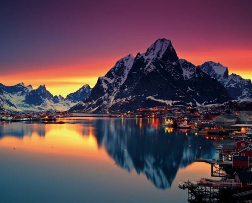 Pueblo de Reine al atardecer con montañas reflejadas en el mar en las islas Lofoten