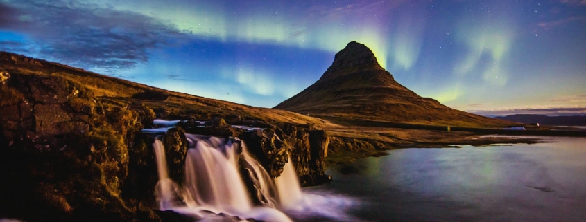 Aurora boreal sobre la montaña Kirkjufell y cascada en la costa de Islandia