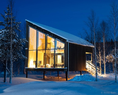 Cabaña moderna de Arctic Bath rodeada de nieve en el bosque de Laponia sueca