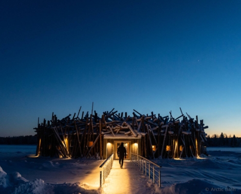 Hotel Arctic Bath iluminado al anochecer sobre el río helado en Laponia sueca