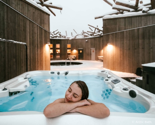 Jacuzzi exterior de Arctic Bath con personas bañándose frente al paisaje invernal, Laponia sueca