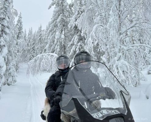 Personas conduciendo motos de nieve entre bosques nevados en Laponia sueca