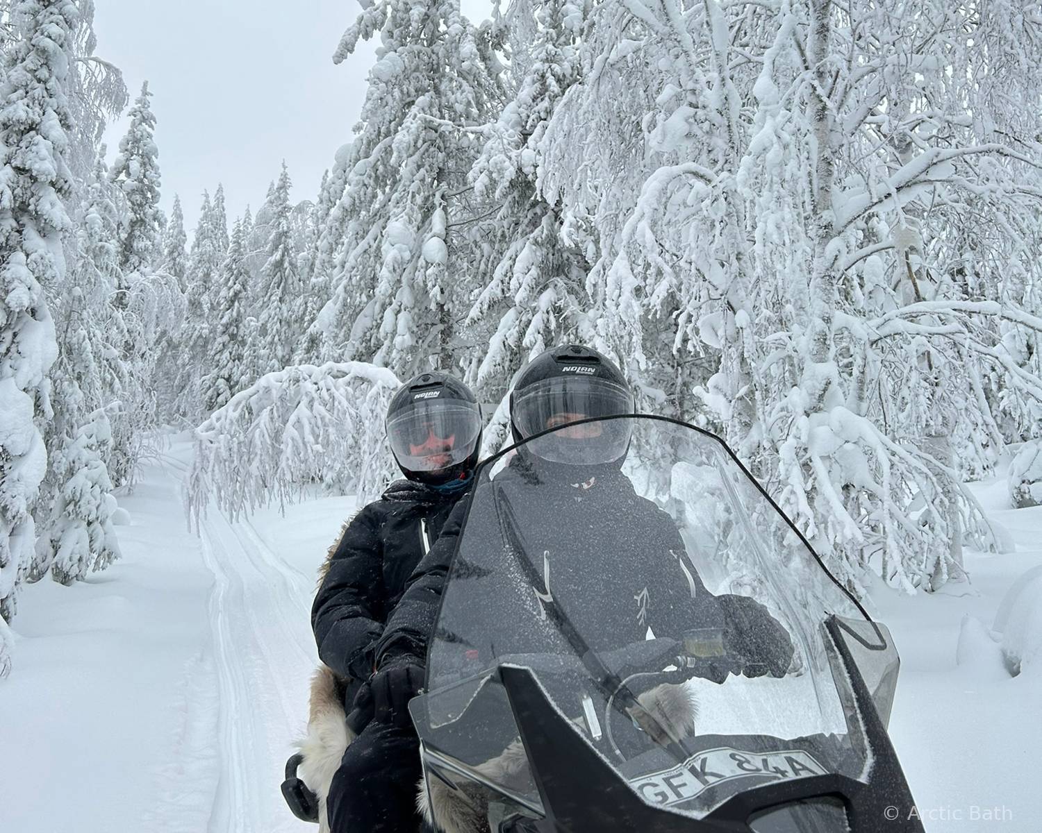 Personas conduciendo motos de nieve entre bosques nevados en Laponia sueca