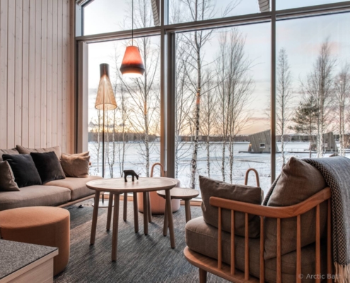 Zona lounge de Arctic Bath con ventanales y vistas al río helado en Laponia sueca