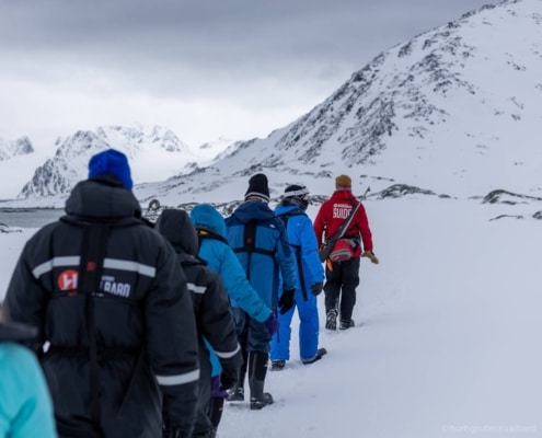 Grupo de pasajeros desembarcando en costa nevada de Svalbard con guías polares