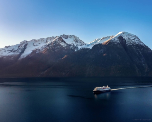 Barco Havila navegando por el Hjørundfjord entre montañas escarpadas