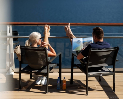 Pasajeros sentados en la cubierta del crucero Havila durante navegación marítima