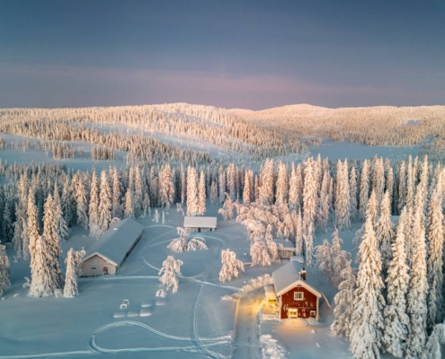 Cabaña roja integrada en paisaje ártico invernal rodeado de nieve y bosque boreal