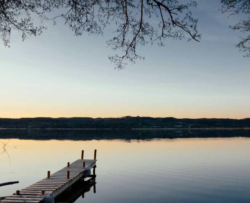 Embarcadero de madera al atardecer sobre lago en paisaje del norte