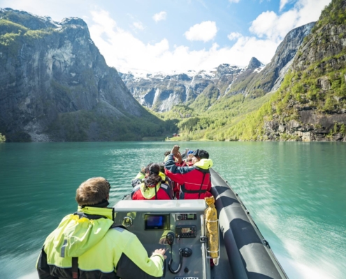 Embarcación RIB navegando por el fiordo con montañas y agua tranquila