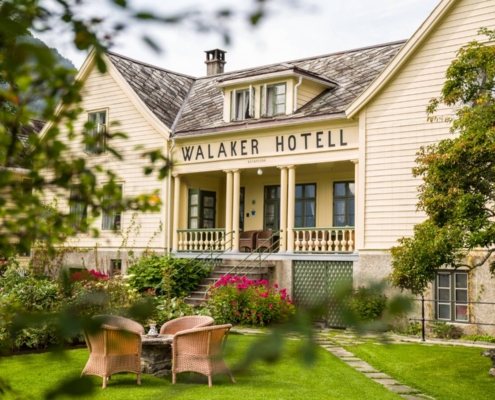 Fachada principal del Walaker Hotel con jardín y porche de madera